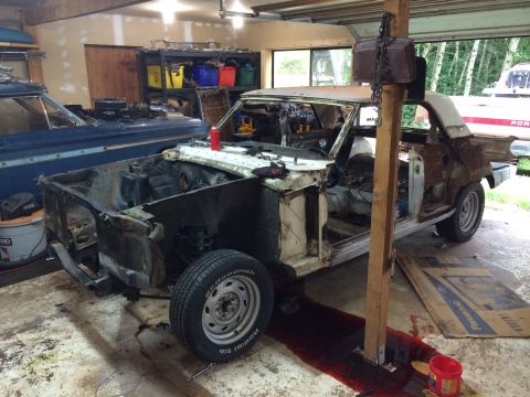 1964 Ford Fairlane - A car in a state of disassembly sits in a garage, with another vehicle partially visible beside it.