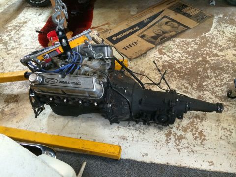 1964 Ford Fairlane - A Ford Racing engine and transmission assembly is suspended by an engine hoist, ready for installation or removal.