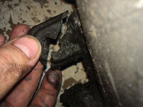 1964 Ford Fairlane - A close-up shows a person's hand holding a piece of a torn rubber seal, with grease and dirt visible.