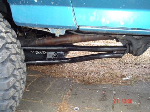 1989 Ford Bronco - Close-up view of the undercarriage of a blue vehicle, showing suspension and a large tire. Text from a watermark is visible.