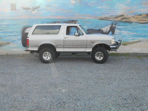 1994 Ford Bronco - A two-door Ford Bronco is parked in front of a mural depicting a beach scene with horses and an eagle.