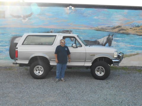 1994 Ford Bronco - Man poses with his silver 1994 Ford Bronco in front of a mural.