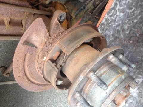 1978 Ford Bronco - Rusty rear axle and brake assembly, showing brake drum and wheel studs. Supermotors.net logo is visible.