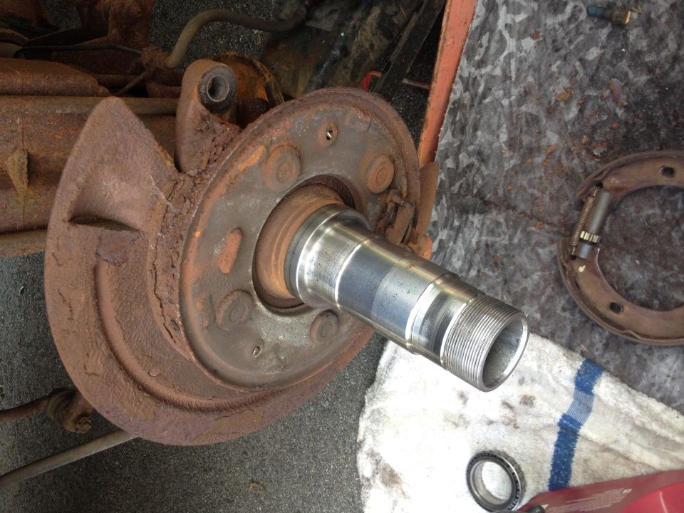 close-up of rusty wheel hub, brake drum, and spindle with threads
