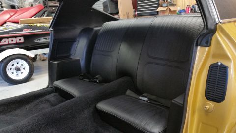 1970 Chevrolet Camaro - The interior of a 1970 Chevrolet Camaro, black vinyl rear seats and carpeting, with a glimpse of the gold exterior.