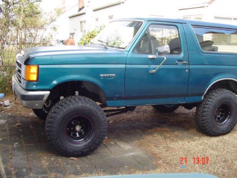 1989 Ford Bronco - This 1989 Ford Bronco is shown from the side, large off-road tires and a teal paint job.