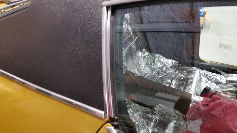 Yellow car's interior, showing a black textured roof and a window covered in aluminum foil insulation