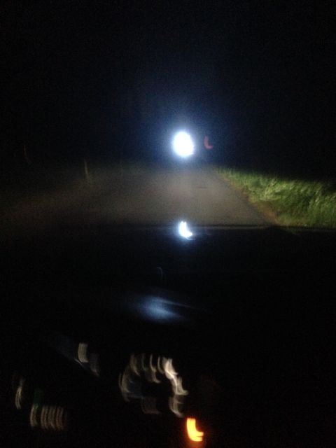 1992 Ford F-150 - Headlights cut through the darkness on a road, with the faint glow of dashboard instruments visible in the foreground.