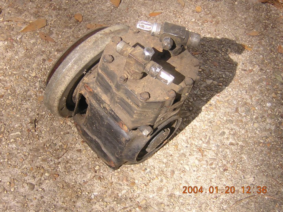 old AC compressor with pulley on a concrete surface