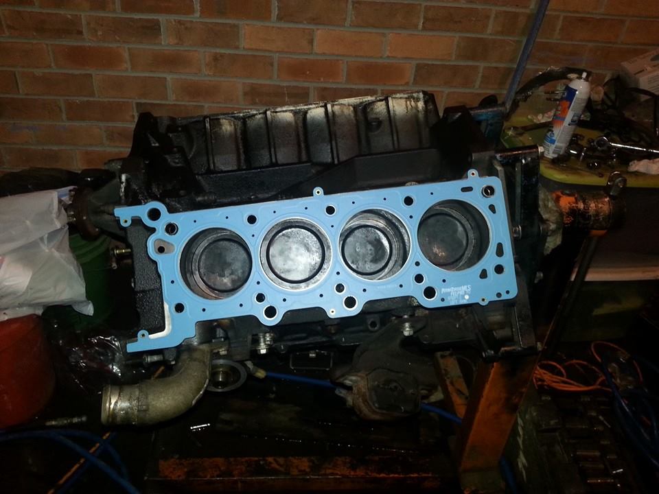 Engine block with gasket and pistons visible