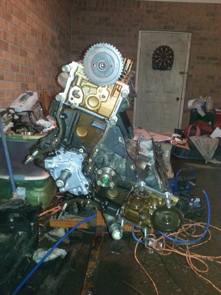 Engine assembly with timing gear visible, resting on a wooden surface