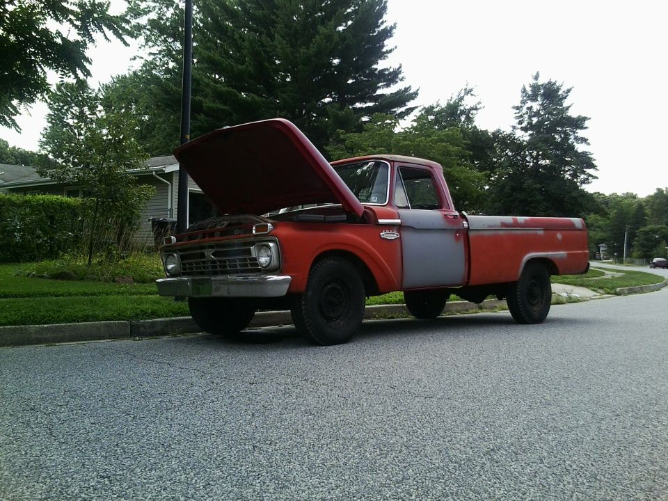 1965 Ford F-100 pickup truck, red cab and front fenders, gray bed, hood open