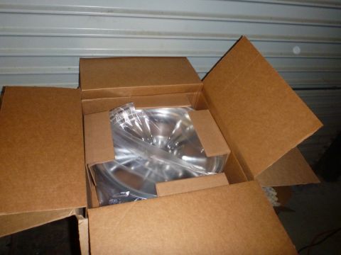1964 Mercury Monterey - A shiny chrome wheel is packaged inside a cardboard box, ready for shipping or storage.