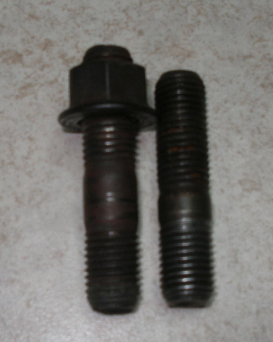 Two metal studs, one with a nut and washer, on a textured surface