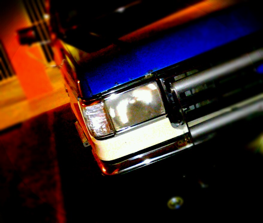 Blue and white Ford Bronco front corner with chrome grille and headlight