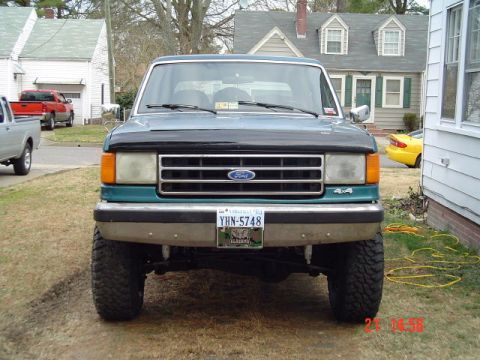 1989 Ford Bronco - This 1989 Ford Bronco is shown from the front, a teal body with a black hood and a prominent chrome grille.