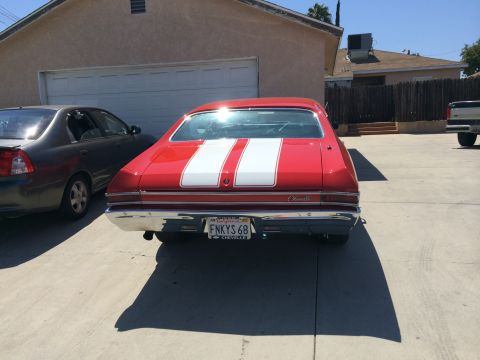 1968 Ford Mustang - The rear of a red 1968 Chevrolet Chevelle SS with dual white racing stripes is visible.