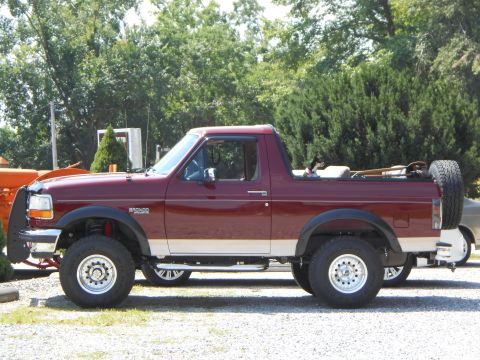 1992 Ford Bronco - Side profile of a maroon 1992 Ford Bronco, a two-tone paint scheme and a rear-mounted spare tire.