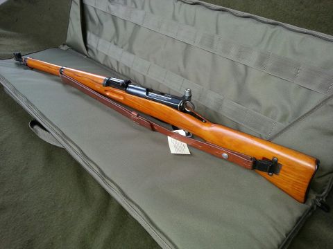 2003 Ford Crown Victoria - Bolt-action rifle with wooden stock and leather sling inside an open gun case.