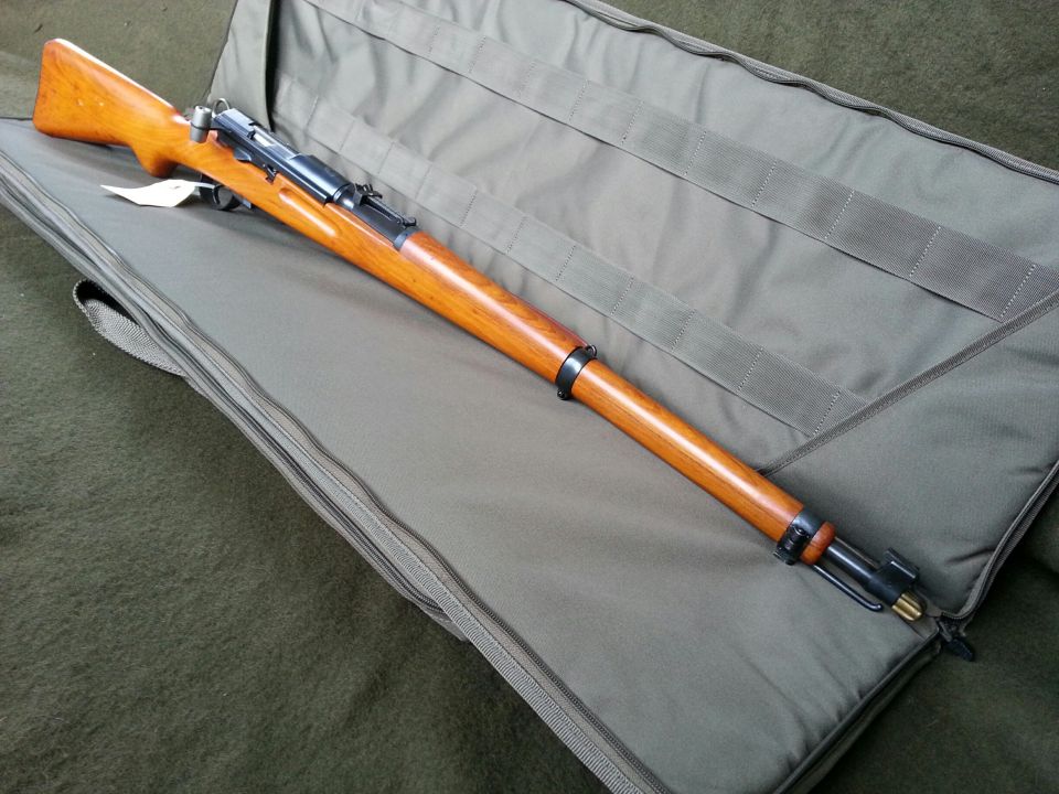 Bolt-action rifle with wooden stock lying on a padded gun case