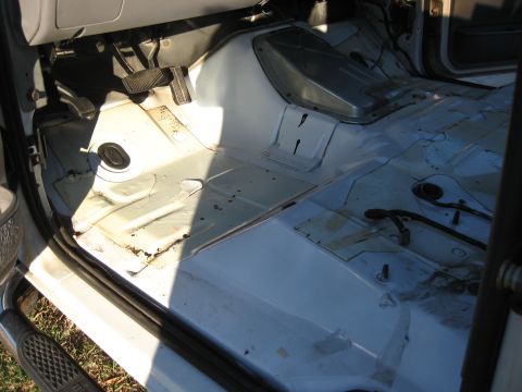 1994 Ford Bronco - The interior floor of a vehicle is shown, with pedals and exposed wiring visible.