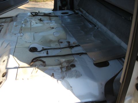 1994 Ford Bronco - The interior floor of a vehicle has been stripped down to the metal, revealing its underlying structure and wiring.