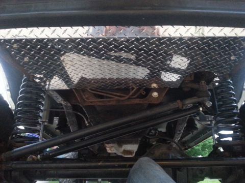 1996 Ford Bronco - Underside view of a vehicle's suspension and a custom diamond plate skid plate.