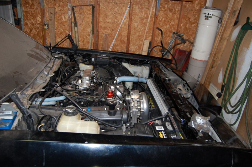 car engine bay with hood open, parts scattered around