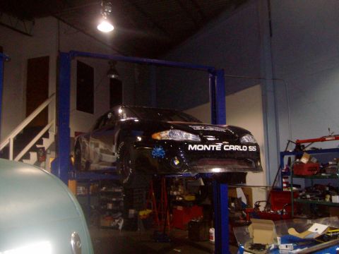 2004 Ford Crown Victoria - A black Chevrolet Monte Carlo SS is elevated on a car lift inside a garage.