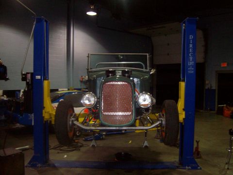 2004 Ford Crown Victoria - A vintage green hot rod is positioned on a car lift in a garage, ready for service.