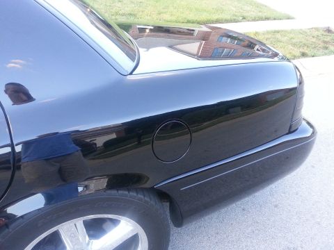 2003 Mercury Marauder - The rear quarter panel of a black 2003 Mercury Marauder is visible, reflecting a brick building.