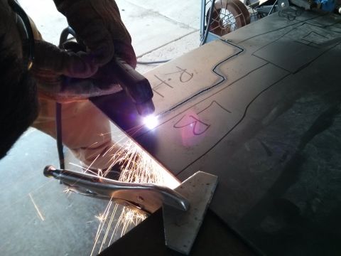 1986 Ford Bronco - Plasma torch cutting a metal sheet with drawn lines and markings.