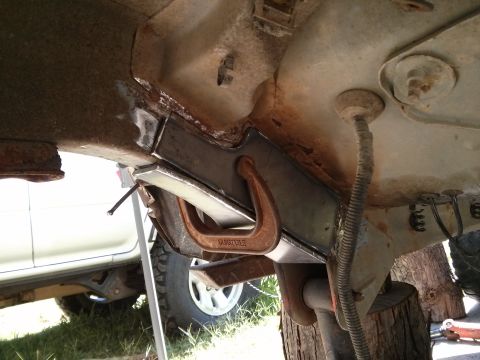 1986 Ford Bronco - Close-up of frame repair work on a vehicle, with a white SUV partially visible in the background.