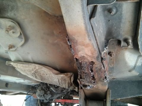 1986 Ford Bronco - The underside of a vehicle shows significant rust damage and welding repairs on the frame.