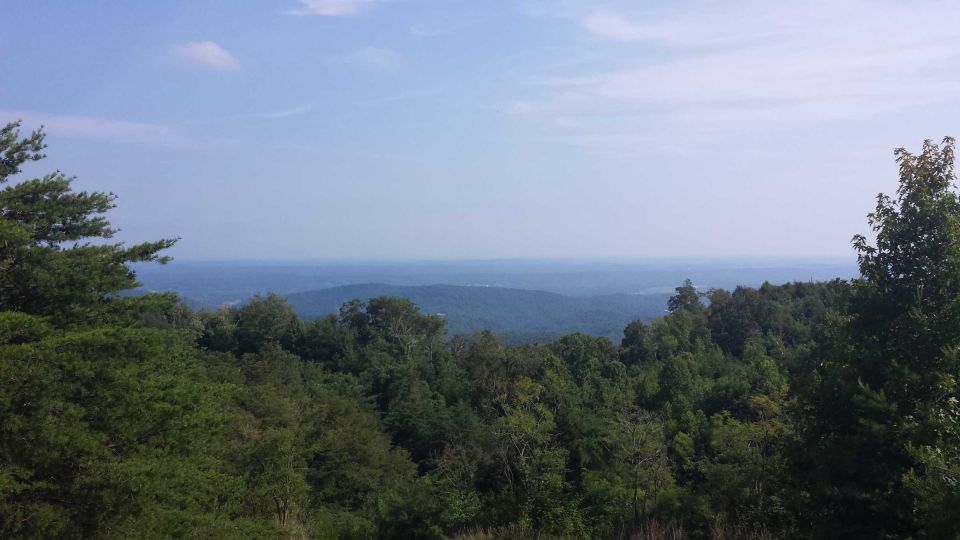 Mountain landscape with trees and a hazy blue sky. Supermotors.net logo in the lower right corner