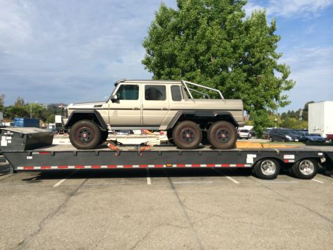 1968 Ford Mustang - A custom six-wheeled Mercedes-Benz G-Wagen is transported on a flatbed trailer under a partly cloudy sky.