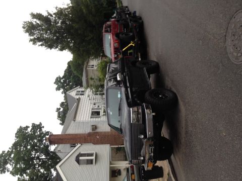 1995 Ford Bronco - A lifted 1995 Ford Bronco and a red Jeep are parked on a residential street.