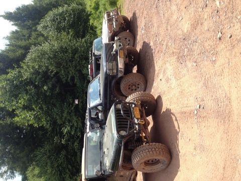 1995 Ford Bronco - A group of off-road vehicles are lined up on a dirt road, ready for an adventure.