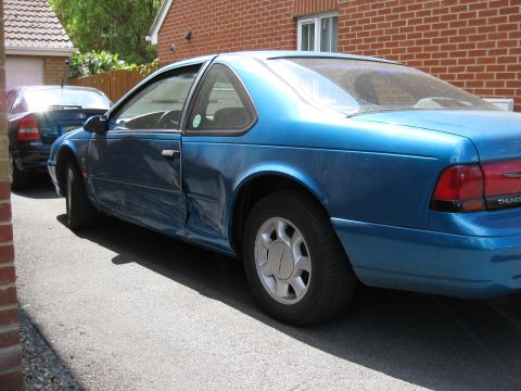 1994 Ford Thunderbird - Blue 1994 Ford Thunderbird coupe parked on a driveway, with another vehicle behind it.