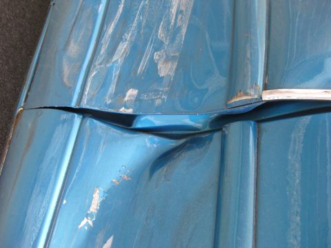 1994 Ford Thunderbird - Close-up of damaged blue car body panels showing a large separation and scuff marks.
