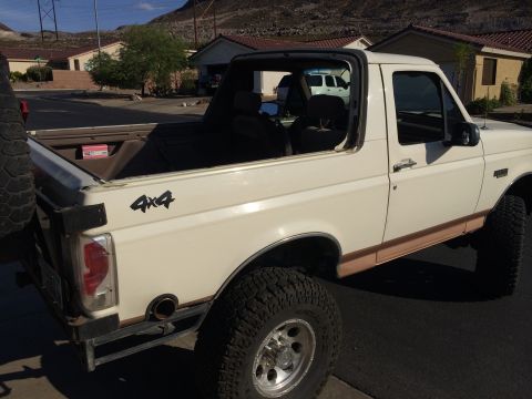 1995 Ford Bronco - This white Ford Bronco features a removable top and a 4x4 decal on its side.