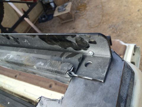 1995 Ford Bronco - Close-up of a damaged white vehicle's metal body panel with visible brackets and bolts.