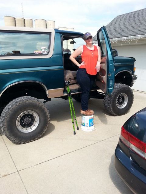 1996 Ford Bronco - Woman poses next to a lifted Ford Bronco, which appears to be from the early 1990s.