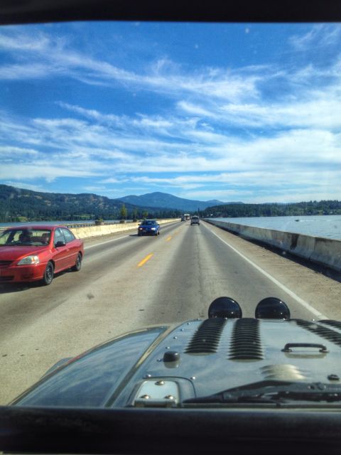 2005 Jeep Wrangler - Driving on a highway with a scenic view of mountains and water under a cloudy blue sky.