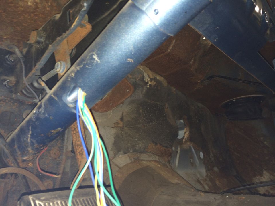 Rusty interior of a vehicle with a blue steering column and exposed wires