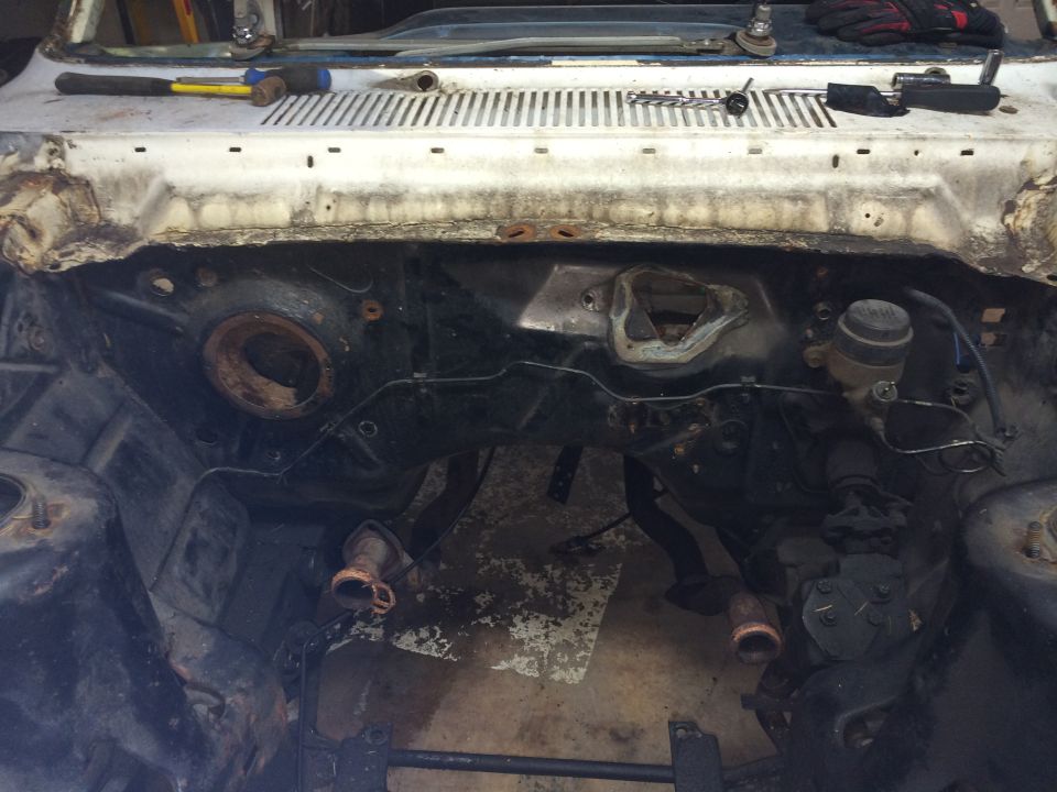 Dismantled car engine bay with tools on the cowl panel