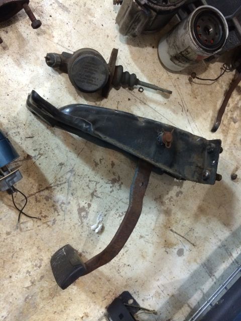 1964 Ford Fairlane - A collection of automotive parts, including a brake pedal assembly and a master cylinder, are laid out on a concrete floor.