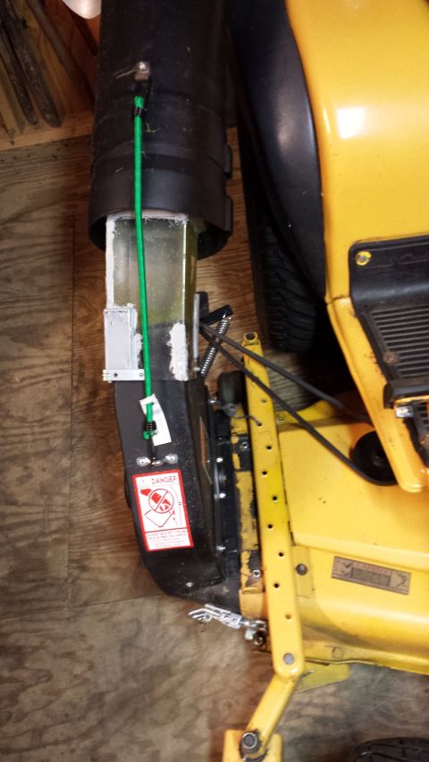 1994 Ford Bronco - Close-up of a yellow lawn mower chute with a green cord and a danger sticker attached.
