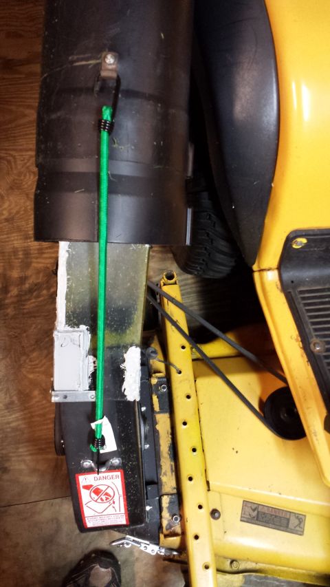 1994 Ford Bronco - Close-up of a lawnmower deck component, secured with a bungee cord and a danger warning label.
