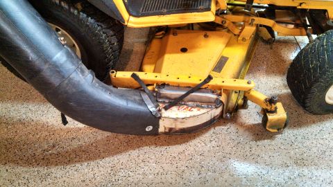 1994 Ford Bronco - Close-up view of a yellow lawn mower deck with a black discharge chute and a tire visible.